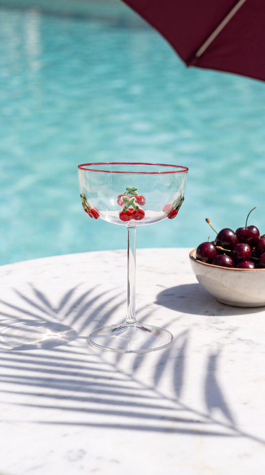 Cherry cocktail glass on a marble table at a sunlit pool club