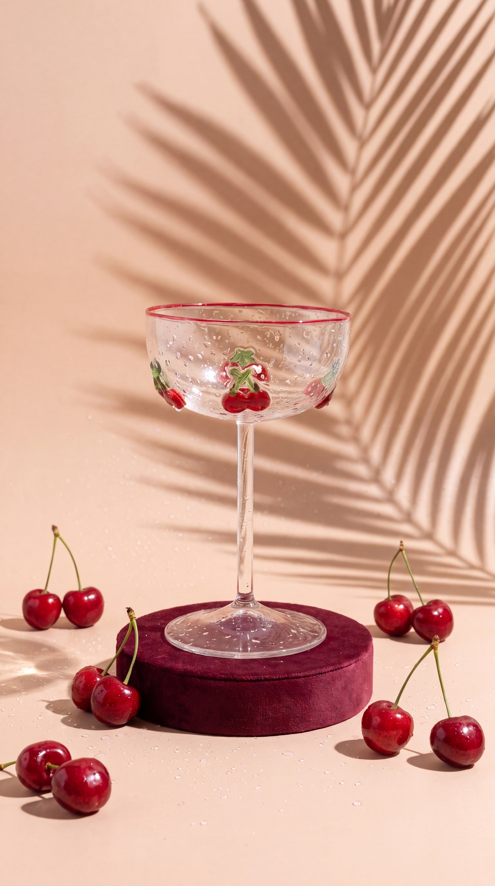 Cherry cocktail glass on a burgundy podium with fresh cherries